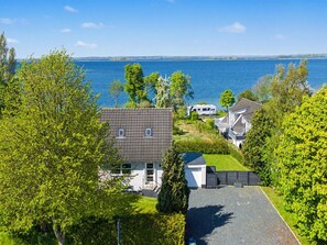Een woonwijk met huizen, een oprit en een waterpartij op de achtergrond.
