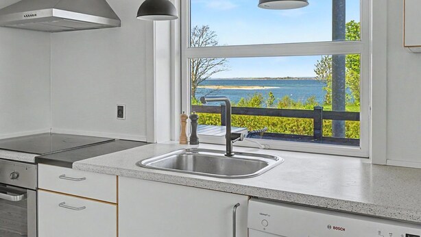 A modern kitchen with a stainless steel range hood, a Bosch dishwasher, and a window with a view of the water. - "Hjort" - 80m from the sea by Interhome (Faaborg)