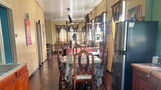 A spacious dining area with wooden tables and chairs, a refrigerator, and a wooden cabinet. - Arlington Apartments (Georgetown)