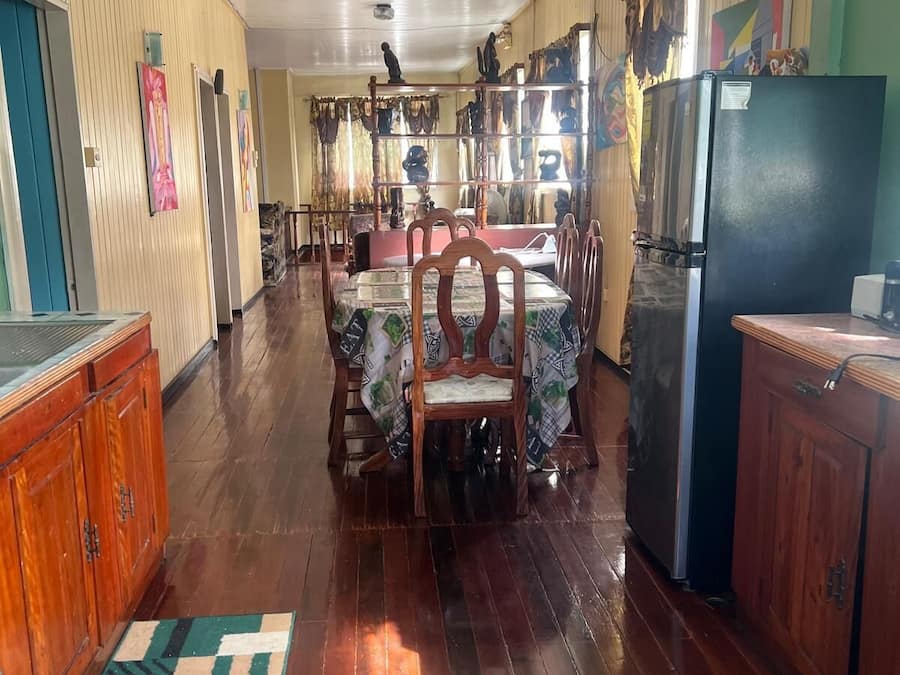 A spacious dining area with wooden tables and chairs, a refrigerator, and a wooden cabinet.