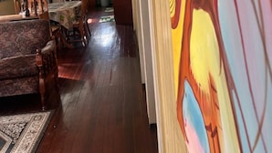 A room with a wooden floor, a dining table with chairs, a sofa, and a painting on the wall. - Arlington Apartments (Georgetown)