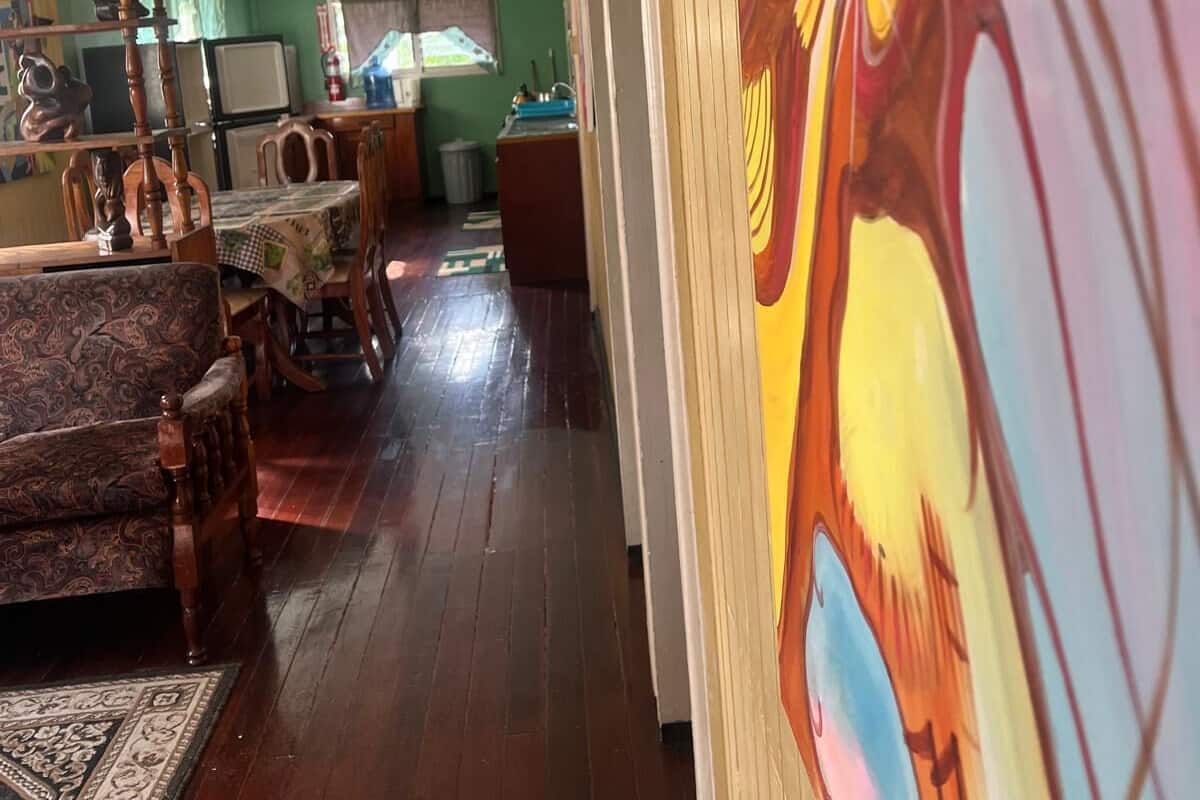 Una habitación con piso de madera, una mesa de comedor con sillas, un sofá y un cuadro en la pared.