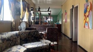 A hallway with a sofa, chairs, a fan, and artwork on the walls. - Arlington Apartments (Georgetown)