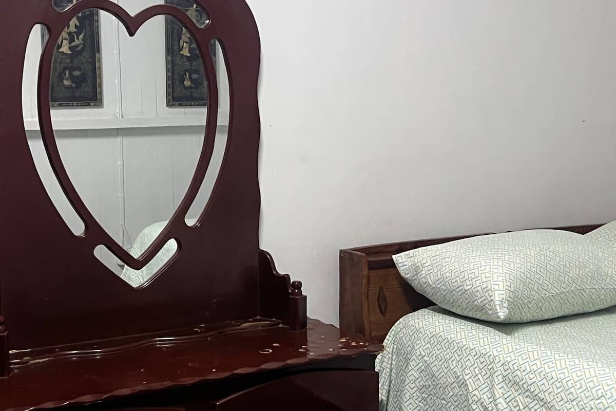 Una cama con un cojín estampado y un cabecero de madera con un espejo con forma de corazón.