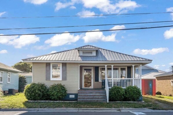 A single-story house with a front porch, a small front yard, and a clear sky. - King's Cottage | Steps from Kure Beach Pier | (Kure Beach)
