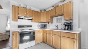 Una cucina con mobili in legno, un forno a microonde, un fornello e una macchina da caffè.