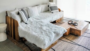 Ein modernes Wohnzimmer mit einer Couch, einer hängenden Rattanleuchte und Wanddekoration aus Gewebe.