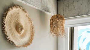 Ein Bett mit weißer Bettwäsche, einem hölzernen Kopfteil und einem Strohhut an der Wand.