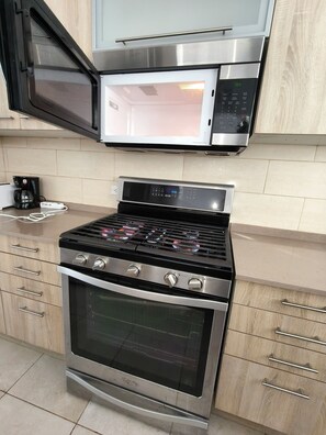 A kitchen with a built-in microwave, a coffee maker, and a stove with a digital display. - Ocean Breeze-2 Bed/2 Bath - Full Kitchen-Pool,5 Stars - ABnB (Sint Maarten)