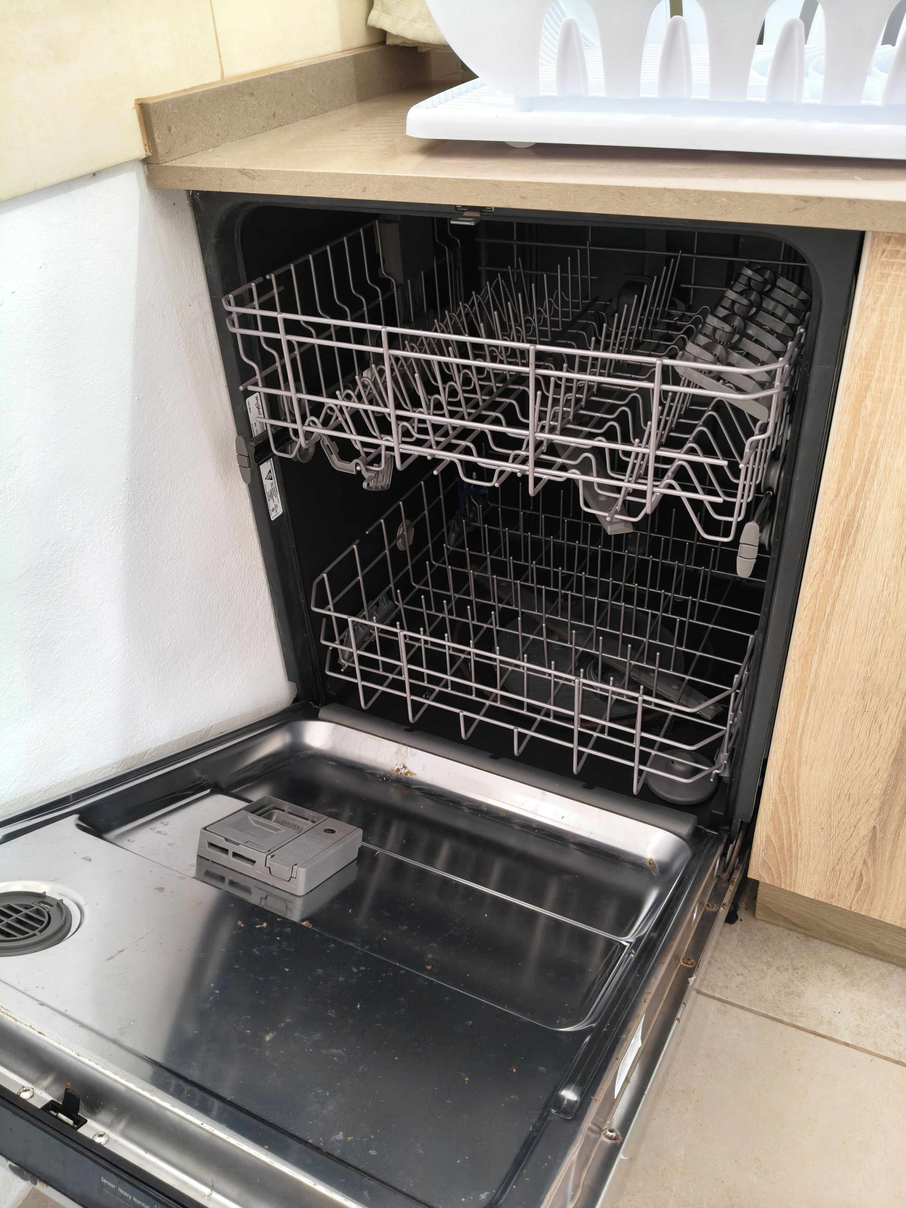 An open dishwasher with racks and a control panel.