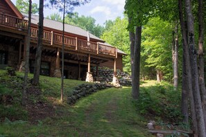 Un chalet avec des fondations en pierre, une terrasse en bois et un mur en pierre.