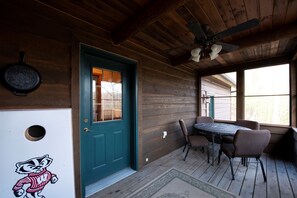 Une cabane en bois avec une porte de couleur turquoise, un ventilateur de plafond, une table avec des chaises et une fenêtre donnant sur un paysage agréable.