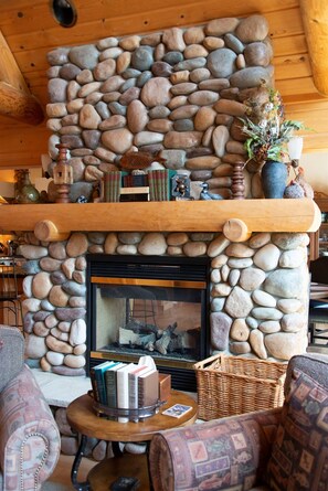A stone fireplace with a mantel shelf, books, and a vase. - The Sanctuary on the Spirit River Flowage (Tomahawk)