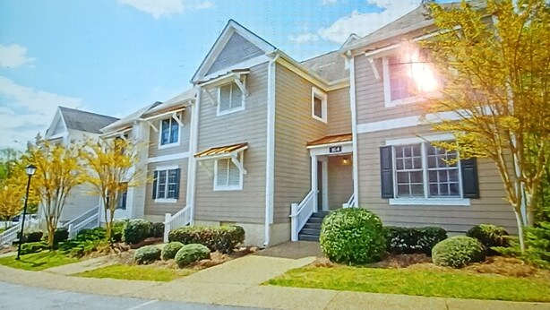 A two-story residential building with a front entrance, a covered porch, and a small front yard with landscaping. - Cozy 2-bedroom townhome in superb Williamsburg with AC and gym access (Williamsburg)