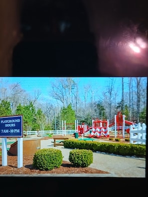 A playground with a sign indicating hours of operation.
