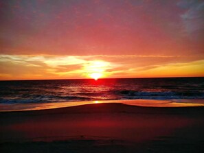 A sunset over the ocean with waves approaching the shore. - BAYSIDE FAMILY RENTAL! TWO UNITS IN ONE! (Peahala Park)