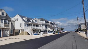 A coastal street lined with multi-story houses, a clear sky, and a view of the ocean in the distance. - BAYSIDE FAMILY RENTAL! TWO UNITS IN ONE! (Peahala Park)
