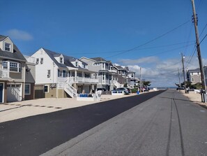 A coastal street lined with multi-story houses, a clear sky, and a view of the ocean in the distance. - BAYSIDE FAMILY RENTAL! TWO UNITS IN ONE! (Peahala Park)