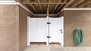 A white door with black hinges, a wooden ceiling, and a green garden hose on the ground. - BAYSIDE FAMILY RENTAL! TWO UNITS IN ONE! (Peahala Park)