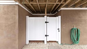 A white door with black hinges, a wooden ceiling, and a green garden hose on the ground. - BAYSIDE FAMILY RENTAL! TWO UNITS IN ONE! (Peahala Park)