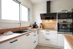 A modern kitchen with a built-in microwave, oven, and sink. - Fauvette des sables - Jolie maison 3 chambres proche de la mer (Saint-Vincent-sur-Jard)
