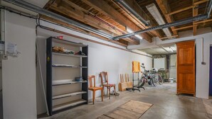 En garage med træbjælker, et arbejdsbord, stole og cykler.