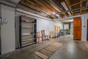 Eine Garage mit Holzbalken, einer Werkbank, Stühlen und Fahrrädern.