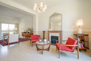 Un salon spacieux doté d’une cheminée, d’un lustre et d’un grand miroir.