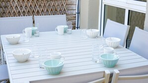 Et hvidt bord dækket med skåle, glas og en kande, omgivet af stole.