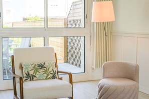 A room with a window, a chair with a cushion, and a floor lamp. - Villa Viasol - superbe villa d'époque (Les Sables d'Olonne)