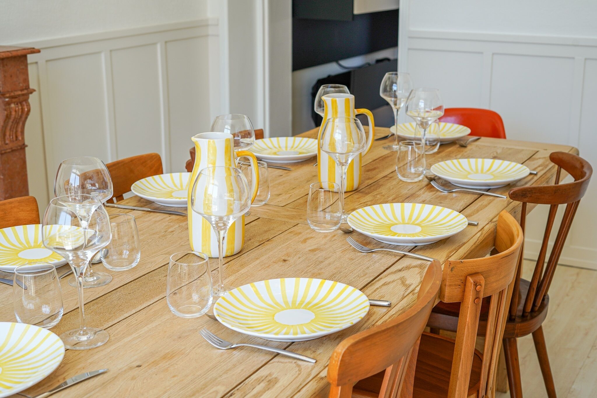 A dining table set with plates, glasses, and a pitcher.
