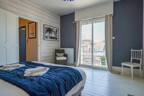 Une chambre à coucher avec un lit, une chaise, un radiateur et une vue sur l’extérieur.