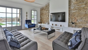 Una sala de estar moderna con una pared de piedra, un televisor grande y vistas al exterior.