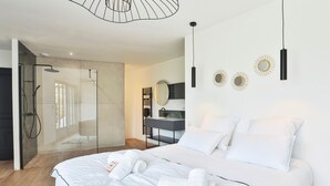 Un dormitorio moderno con una cama grande, zona de ducha y tocador con espejo.