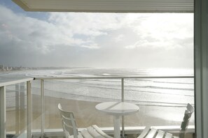 A balcony with a glass railing, a small round table, and two white chairs. - Aigue Marine - avec vue spectaculaire sur l'océan (Les Sables d'Olonne)