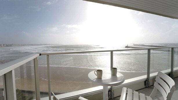 A balcony with a table and chairs overlooking a beach. - Aigue Marine - avec vue spectaculaire sur l'océan (Les Sables d'Olonne)