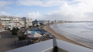 A coastal cityscape with a beach, buildings, and a clear sky. - Aigue Marine - avec vue spectaculaire sur l'océan (Les Sables d'Olonne)