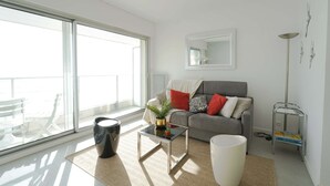 A modern living room with a sofa, coffee table, and a large window. - Aigue Marine - avec vue spectaculaire sur l'océan (Les Sables d'Olonne)
