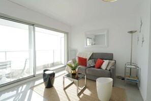 Ein modernes Wohnzimmer mit einer Couch, einem Couchtisch und einem großen Fenster.