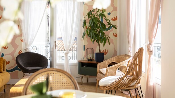 Ein Zimmer mit Korbmöbeln, einem Blumentopf und Blick ins Freie.
