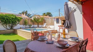 Eine Terrasse mit Esstisch, Pool und roter Wand.