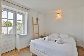 A bedroom with a bed, a window, a ladder, and a wall-mounted light fixture. - Longe 17 - élégante propriété avec deux maisons (Longeville-sur-Mer)