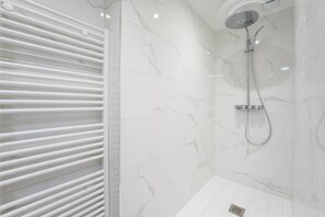 A modern bathroom with a shower, white marble tiles, and a white towel rack. - Beluga - One Bedroom Apartment, Sleeps 4 (Les Sables d'Olonne)