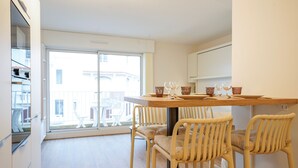 A modern kitchen with a dining area, large windows, and a view of the outside. - Beluga - pied-à-terre idéal sur la côte vendéenne (Les Sables d'Olonne)
