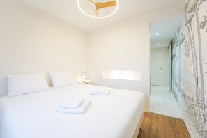 A hotel room with a large bed, a bedside table, a wall-mounted light, and a mural on the adjacent wall. - Beluga - One Bedroom Apartment, Sleeps 4 (Les Sables d'Olonne)