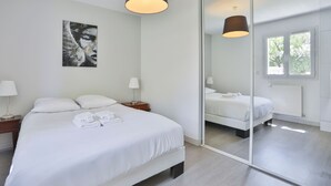 Une chambre d’hôtel moderne avec un grand lit, des tables de chevet, un miroir et une fenêtre.