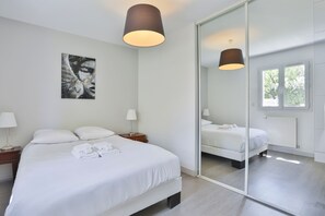 A modern hotel room with a large bed, bedside tables, a mirror, and a window. - L'Orangerie des Sables (Les Sables d'Olonne)