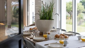A dining table set with plates, glasses, and croissants, with a large white bowl of green plants in the center. - Villa Mediterranée - Three Bedroom House, Sleeps 8 (Les Sables d'Olonne)