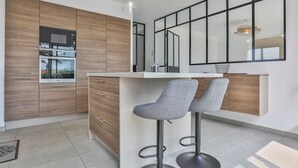 A modern kitchen with wooden cabinets, a built-in microwave, and a large window. - Villa Mediterranée - Three Bedroom House, Sleeps 8 (Les Sables d'Olonne)