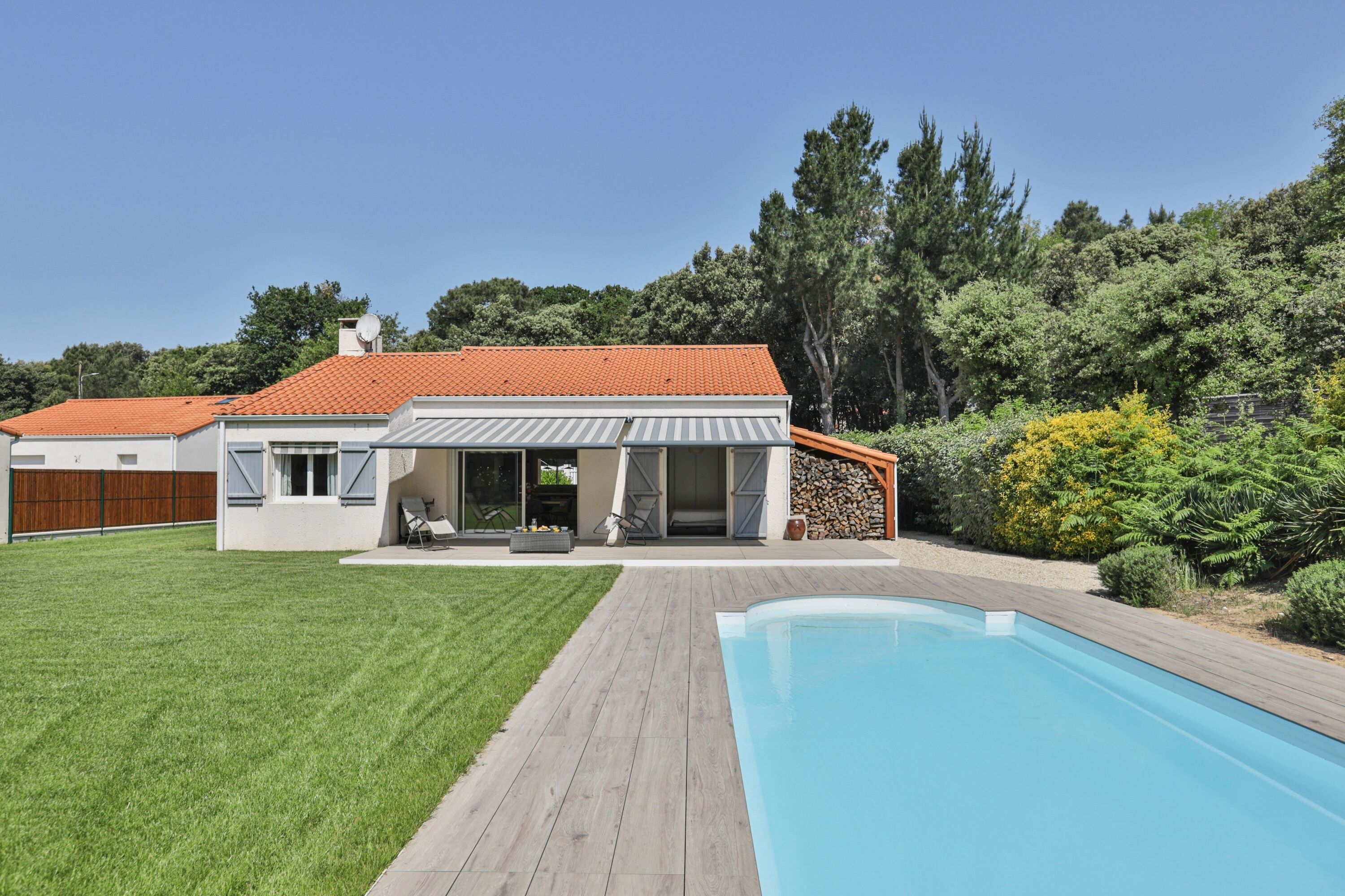 A modern house with a swimming pool, a covered patio, and a well-maintained lawn.